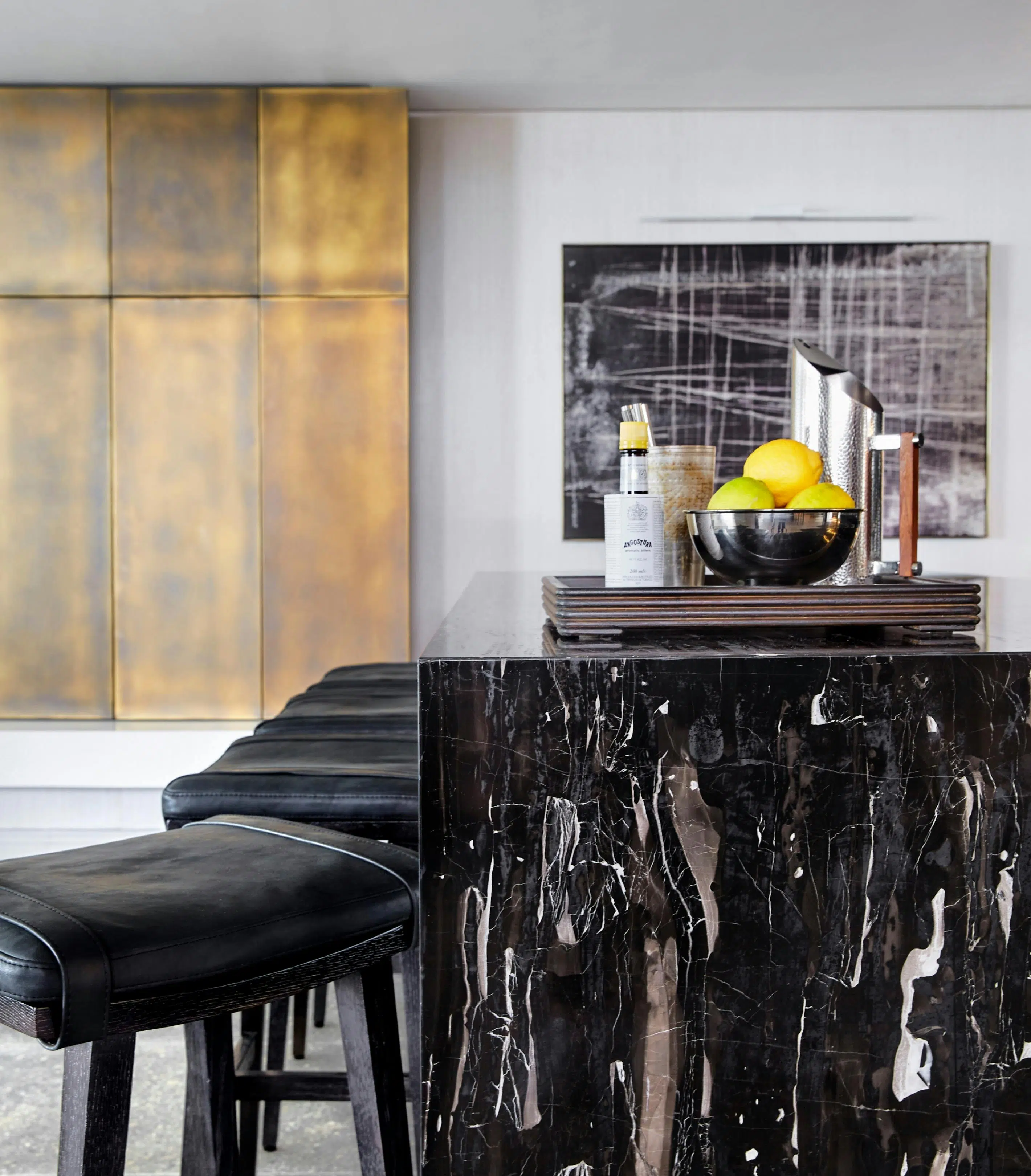 A waterfall, black marble bar with bar stools to the left and artwork with a similar pattern to the marble in the background.