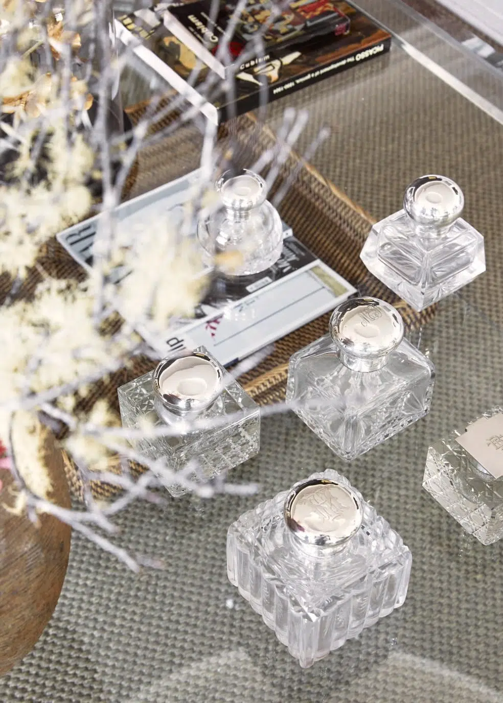 Elegant glass bottles displayed on a coffee table adorned with decorative branches and books.